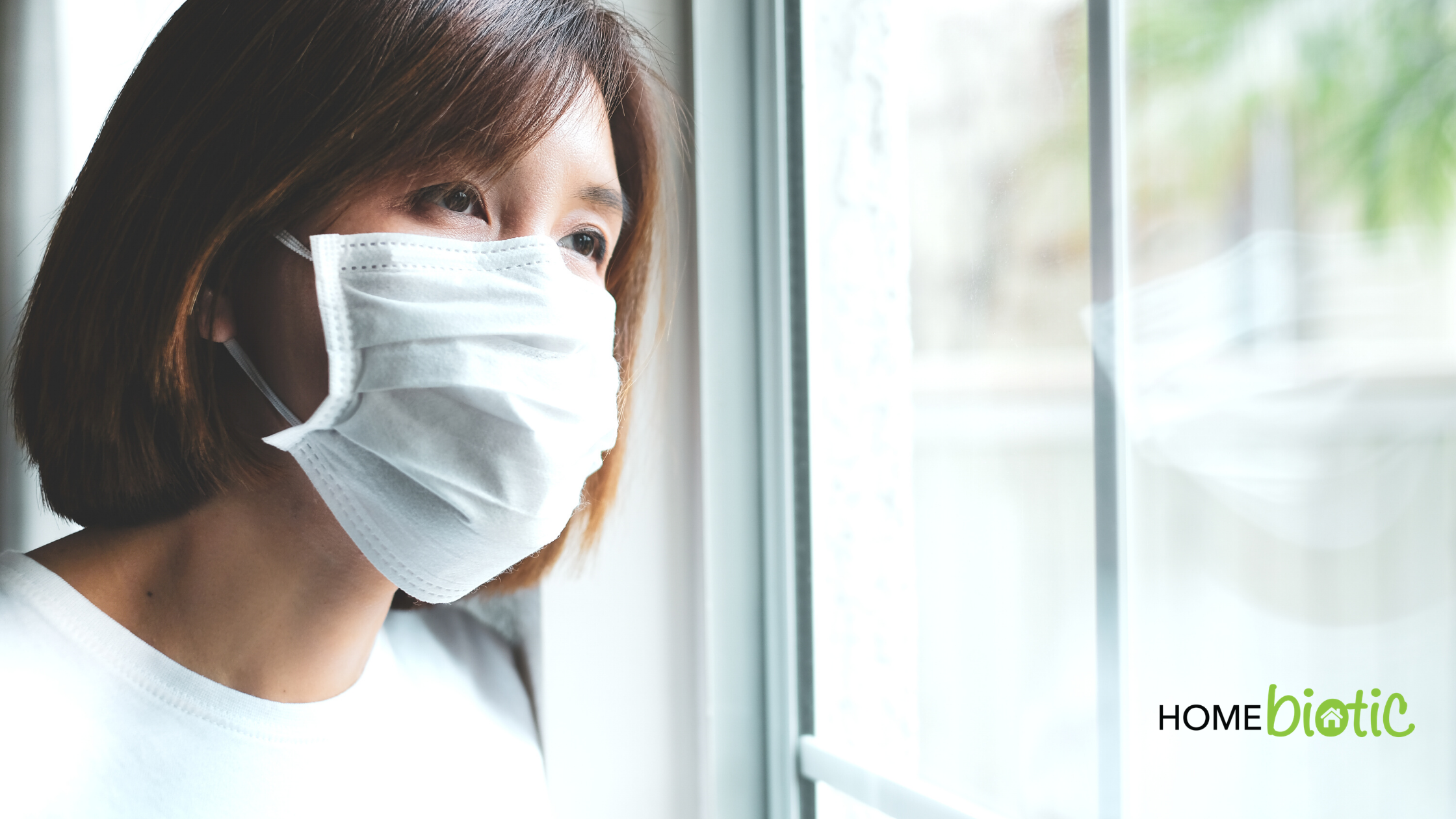 How Social Isolation Impacts Mold Growth at Home | Woman wearing a mask looking out a window