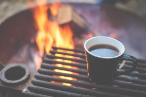 cup of coffee by a campfire