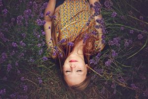 woman laying in field of purple flowers - homebiotic