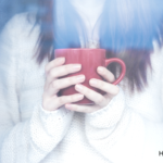 What Causes Mold: Winter Edition | Woman holding a mug inside of foggy window