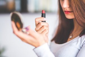 girls holding red lipstick and looking in handheld mirror - Homebiotic - the dangers of Phthalates